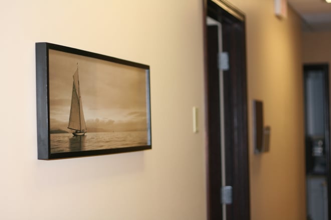 A close-up of a hallway wall in a clinic decorated with a framed black-and-white photograph of a sailboat.