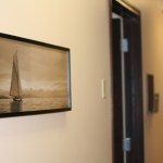 A close-up of a hallway wall in a clinic decorated with a framed black-and-white photograph of a sailboat.